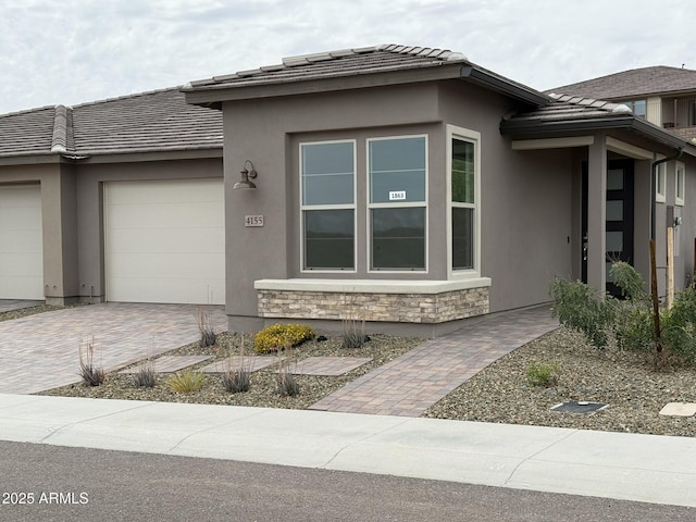 4155 Desert Moon Dr, Wickenburg, AZ 85390 - view of side of property with an attached garage, a tile roof, decorative driveway, stucco siding, and stone siding