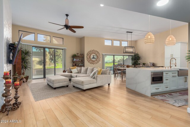 living room featuring light hardwood / wood-style floors, ceiling fan, and sink