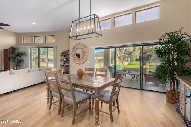 dining space with plenty of natural light, light hardwood / wood-style floors, and a towering ceiling