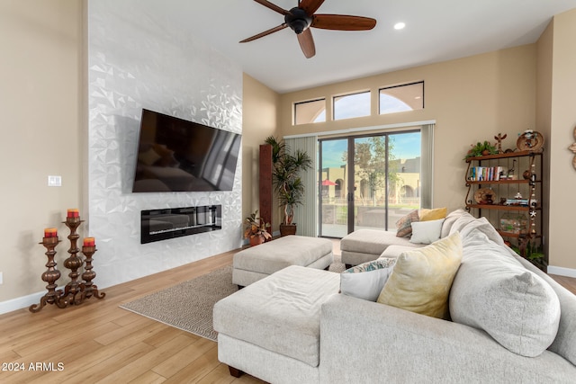 living room featuring ceiling fan, a fireplace, and wood-type flooring