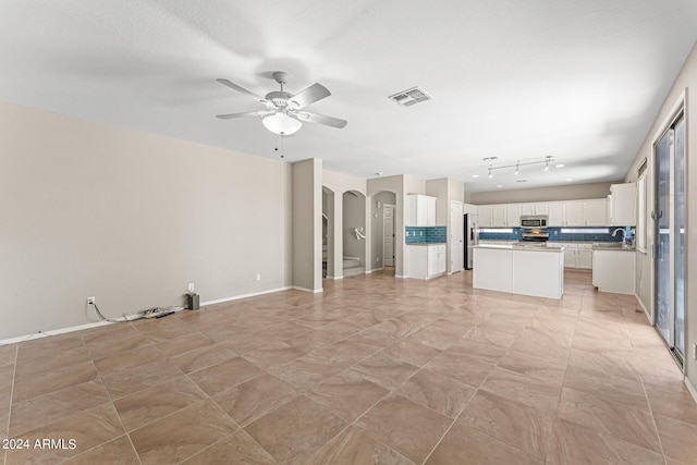 unfurnished living room with a textured ceiling, ceiling fan, and sink