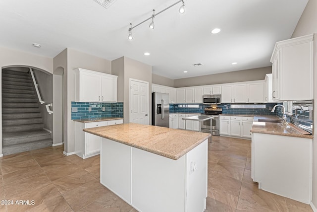 kitchen with white cabinetry, a center island, stainless steel appliances, and sink