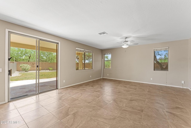 spare room with ceiling fan, a healthy amount of sunlight, and a textured ceiling