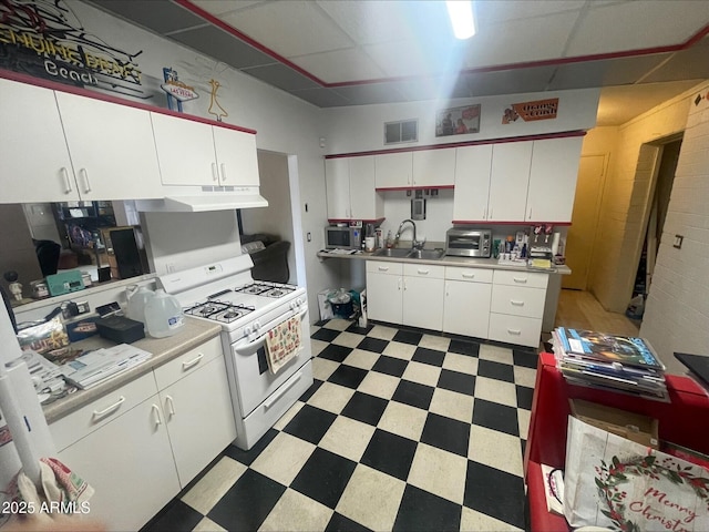 kitchen with visible vents, light floors, white range with gas stovetop, white cabinetry, and stainless steel microwave
