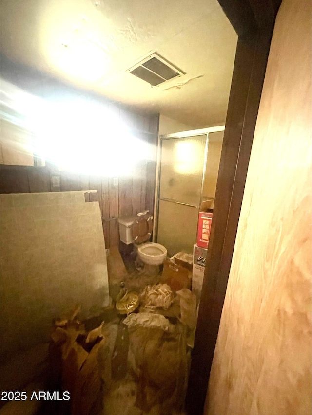 bathroom with a walk in shower, toilet, and visible vents