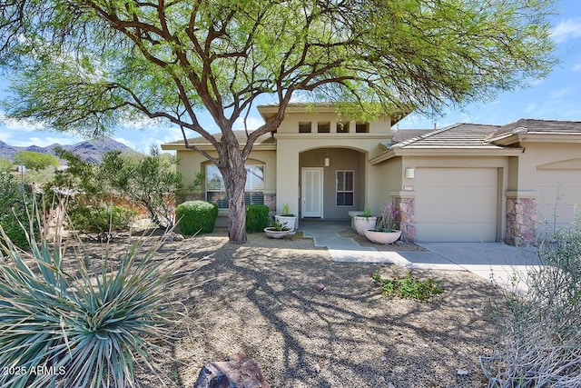 mediterranean / spanish house with a mountain view, an attached garage, driveway, and stucco siding