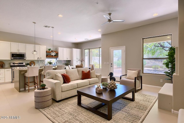 living room featuring visible vents, a ceiling fan, baseboards, and recessed lighting