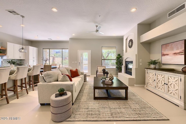 living area featuring a large fireplace, a ceiling fan, recessed lighting, and visible vents