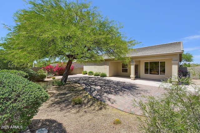 view of front facade featuring fence, a patio area, and stucco siding