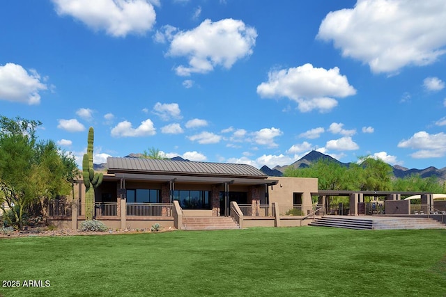 back of house with a lawn and a mountain view