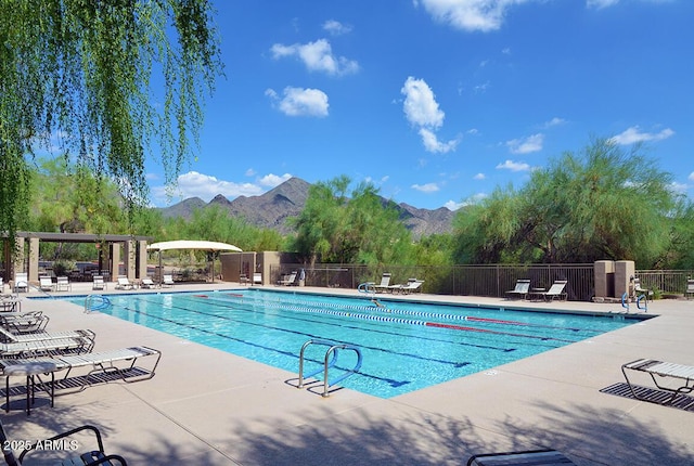 pool with a patio, a mountain view, and fence