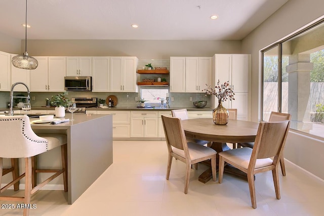 kitchen with a sink, open shelves, appliances with stainless steel finishes, and tasteful backsplash