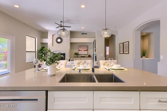 kitchen with visible vents, a sink, white cabinets, open floor plan, and dishwashing machine