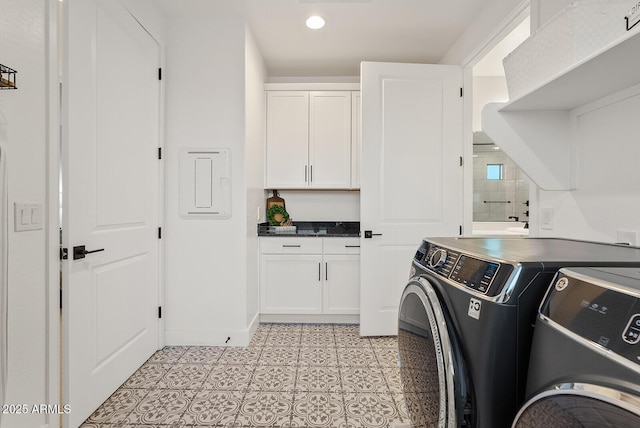 clothes washing area featuring cabinets, light tile patterned flooring, and washing machine and clothes dryer