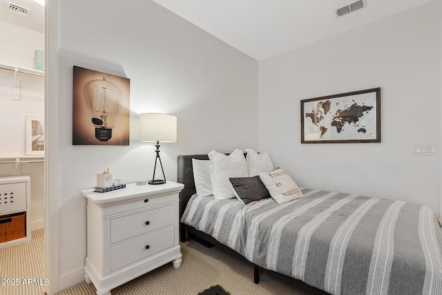 bedroom featuring heating unit, light colored carpet, a walk in closet, and a closet