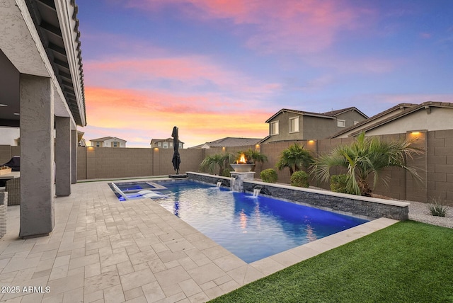 pool at dusk with pool water feature and a patio area