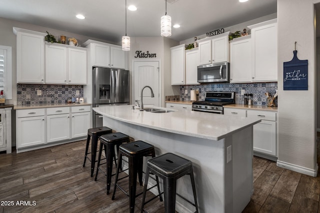 kitchen featuring a sink, white cabinetry, a breakfast bar, dark wood finished floors, and stainless steel appliances