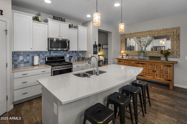 kitchen with decorative backsplash, stainless steel appliances, dark wood-type flooring, white cabinetry, and a sink