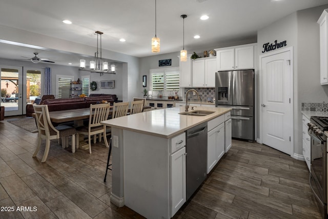 kitchen with backsplash, a sink, dark wood finished floors, stainless steel appliances, and ceiling fan