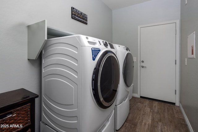 clothes washing area with baseboards, wood finished floors, laundry area, and washer and dryer