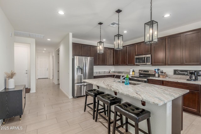 17973 W Ashley Dr, Goodyear, AZ 85338 - kitchen with stainless steel appliances, a sink, dark brown cabinets, light stone counters, and recessed lighting