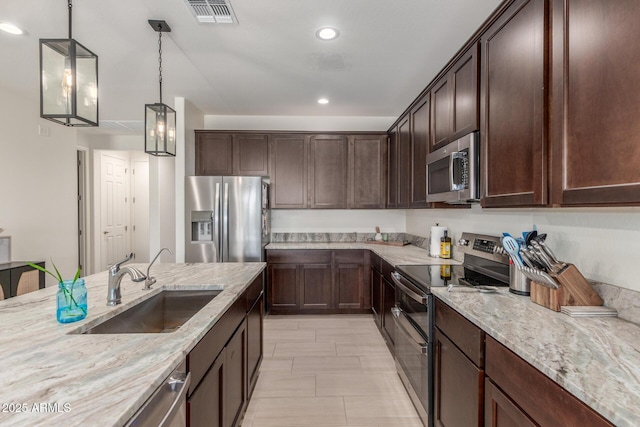 17973 W Ashley Dr, Goodyear, AZ 85338 - kitchen with stainless steel appliances, a sink, dark brown cabinets, light stone counters, and recessed lighting