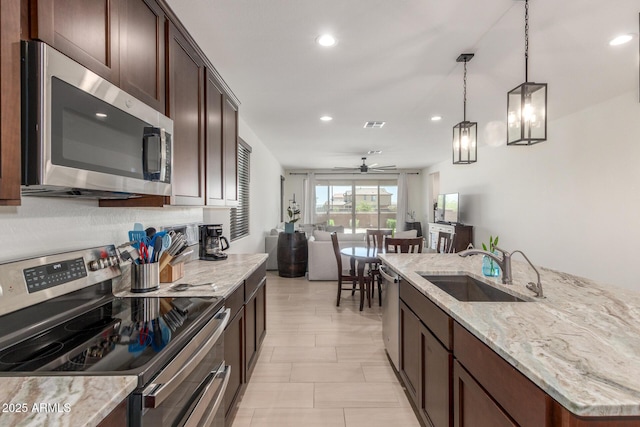 17973 W Ashley Dr, Goodyear, AZ 85338 - kitchen with stainless steel appliances, a sink, dark brown cabinets, a ceiling fan, and open floor plan