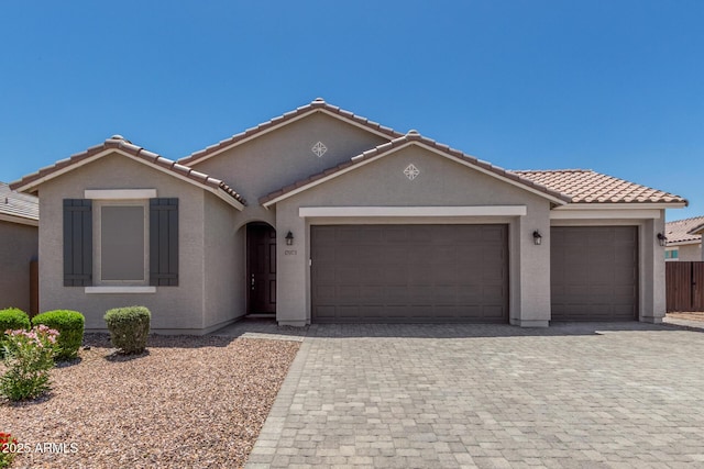 17973 W Ashley Dr, Goodyear, AZ 85338 - view of front facade featuring a garage, decorative driveway, a tiled roof, and stucco siding