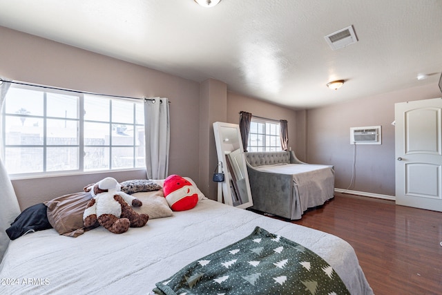 bedroom with dark hardwood / wood-style flooring and a wall mounted air conditioner