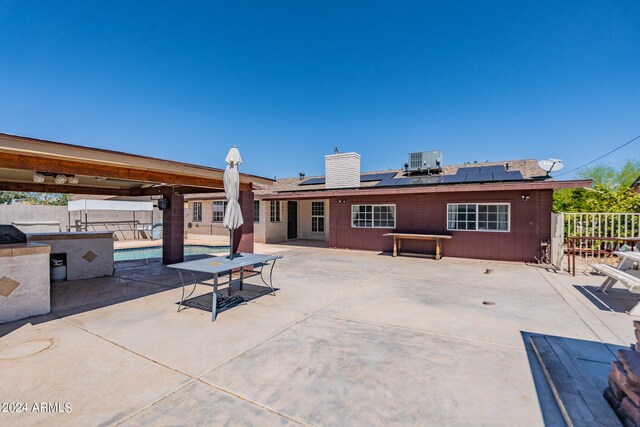 rear view of house with a fenced in pool, a patio area, solar panels, and central AC unit