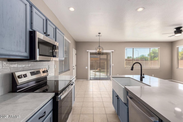 8795 W Windsor Dr, Peoria, AZ 85381 - kitchen featuring stainless steel appliances, a sink, backsplash, light countertops, and decorative light fixtures