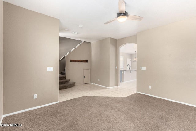 8795 W Windsor Dr, Peoria, AZ 85381 - unfurnished living room featuring a ceiling fan, arched walkways, carpet floors, tile patterned floors, and stairway