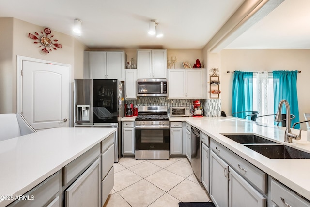 kitchen featuring gray cabinets, light tile patterned flooring, sink, decorative backsplash, and stainless steel appliances