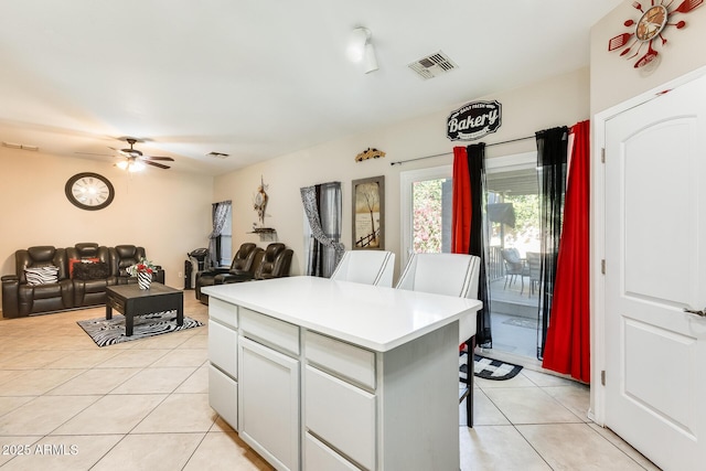 kitchen featuring light tile patterned flooring, ceiling fan, a center island, and a breakfast bar area