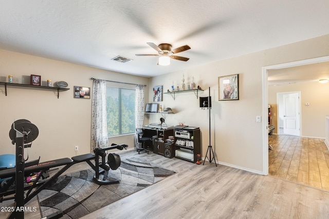 exercise area featuring a textured ceiling, light hardwood / wood-style floors, and ceiling fan