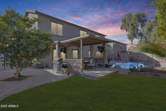 back house at dusk featuring a fenced in pool, a yard, and a patio area