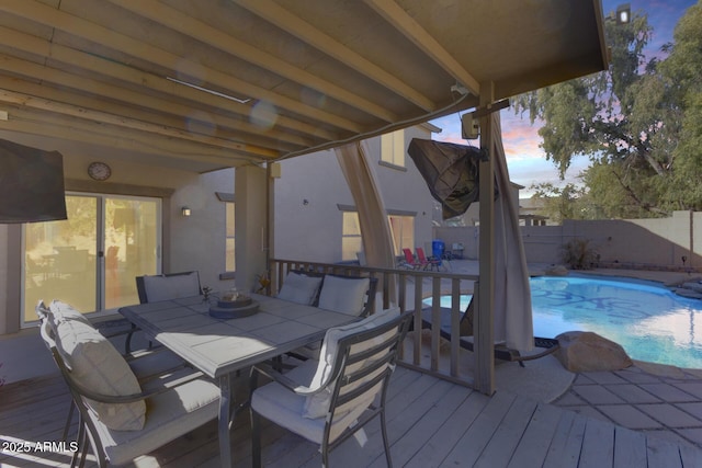 deck at dusk with a fenced in pool