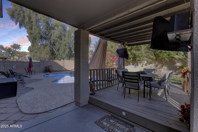 deck at dusk with a fenced in pool