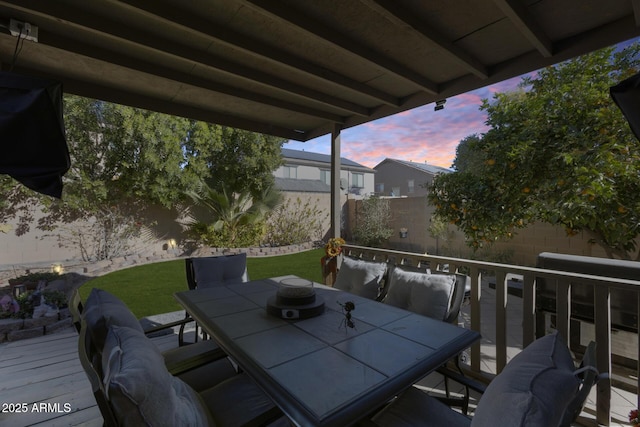 patio terrace at dusk featuring a wooden deck and a yard