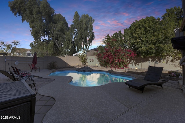 pool at dusk with a patio area