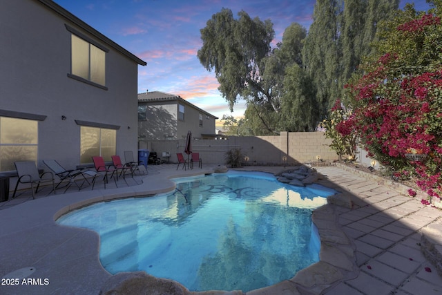 pool at dusk featuring a patio