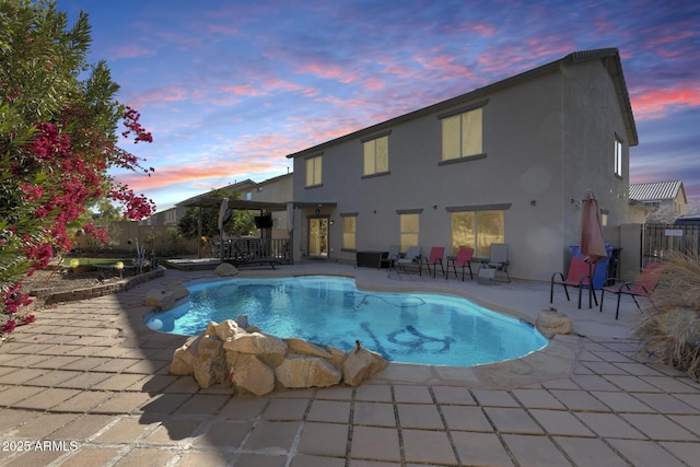 pool at dusk with a patio area