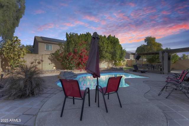 pool at dusk featuring a pergola and a patio area