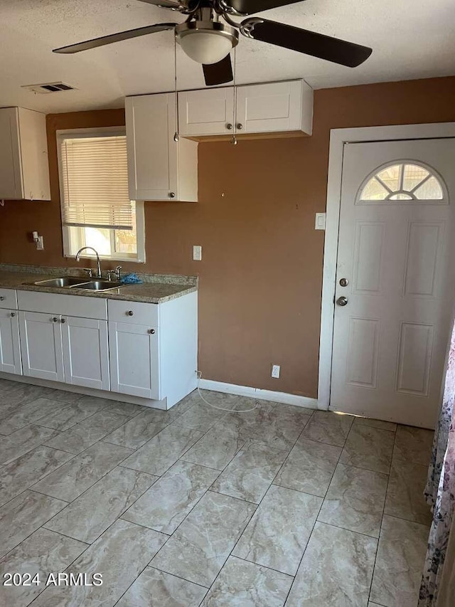 kitchen featuring ceiling fan, sink, white cabinets, and a textured ceiling