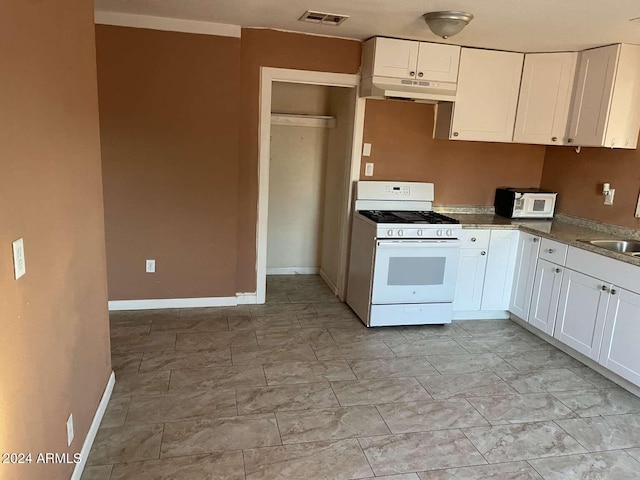 kitchen featuring white range with gas stovetop, white cabinets, and sink