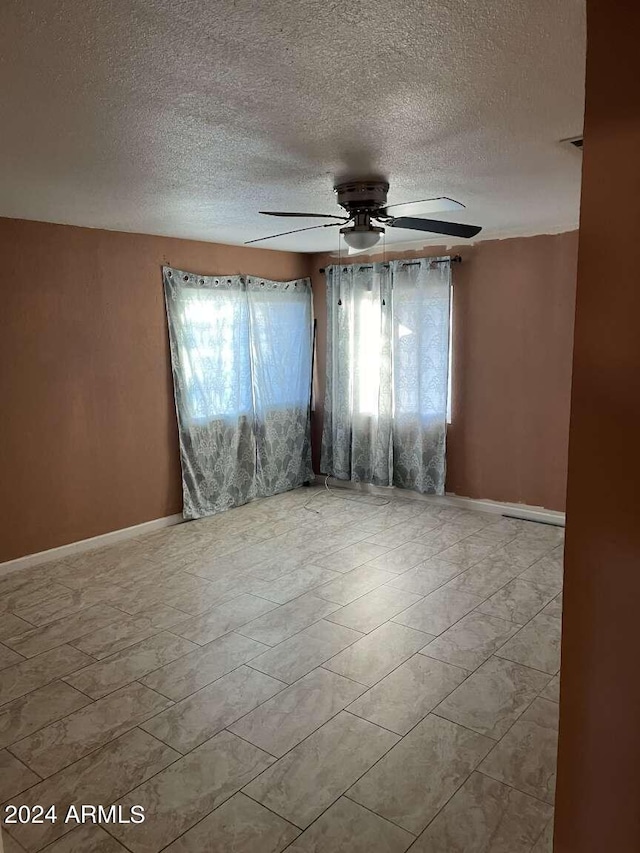 unfurnished room featuring a textured ceiling, plenty of natural light, and ceiling fan