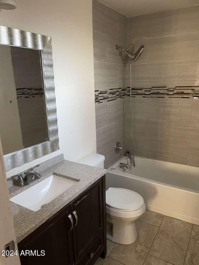 full bathroom featuring vanity, tiled shower / bath combo, toilet, and tile patterned flooring