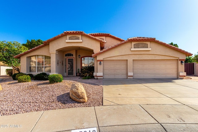 mediterranean / spanish house with a tile roof, concrete driveway, a garage, and stucco siding