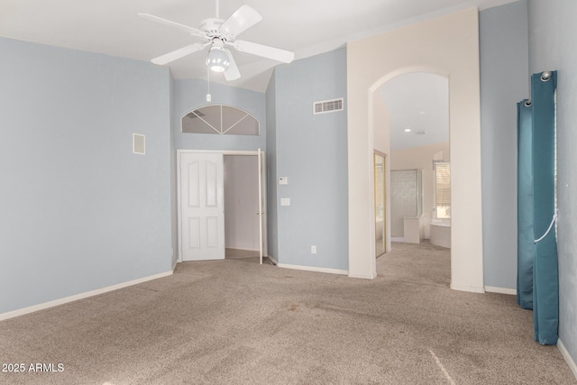 unfurnished bedroom featuring arched walkways, visible vents, carpet flooring, and baseboards