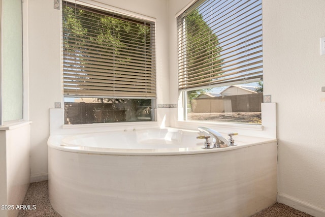 bathroom with a bath and baseboards